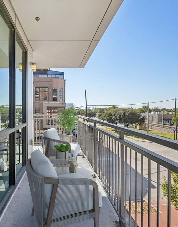 A balcony with a table and chairs overlooking a cityscape.