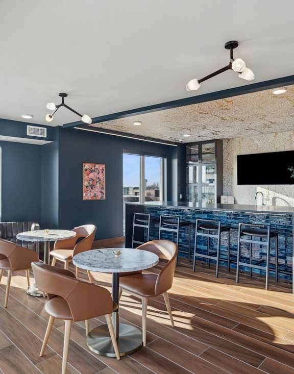 a dining room with tables and chairs and a bar in the background