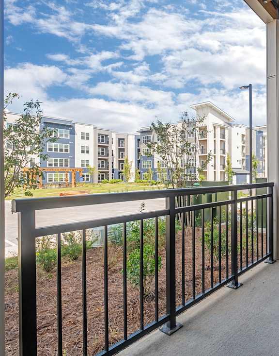 A balcony with a chair and table overlooking a building at The Percy Apartments, Nashville, TN, 37214