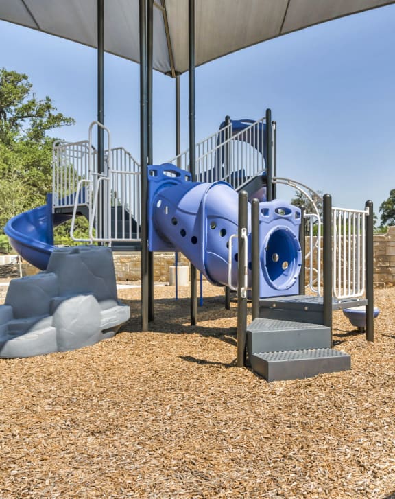 a playground with a blue slide and climbing equipment in a park