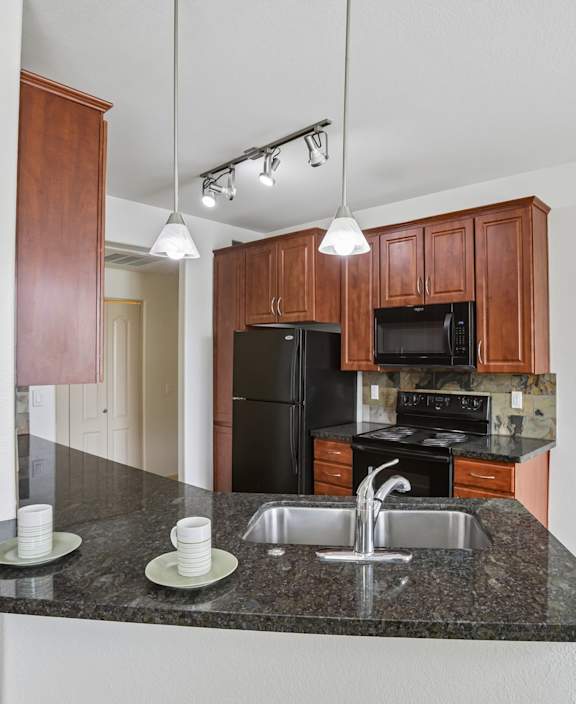 A kitchen with granite countertops and wooden cabinets.