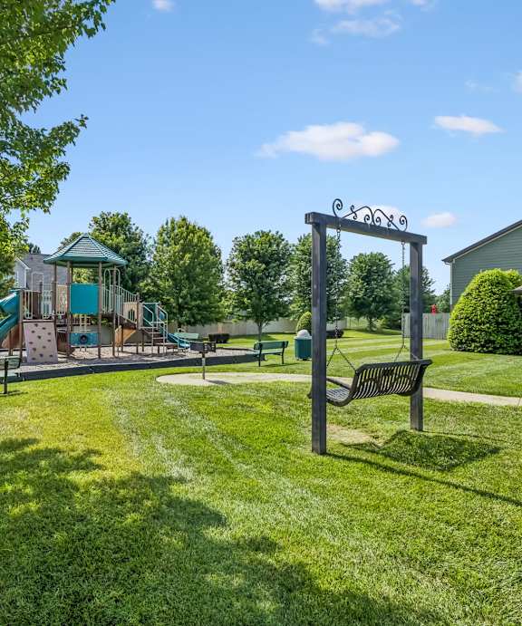 A playground with a swing set and a slide in a grassy area.
