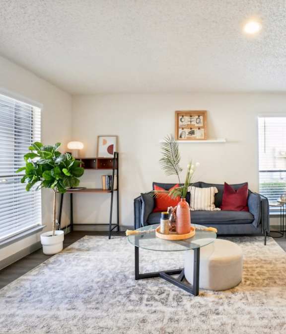 A living room with a grey couch, a glass coffee table, and a fireplace.