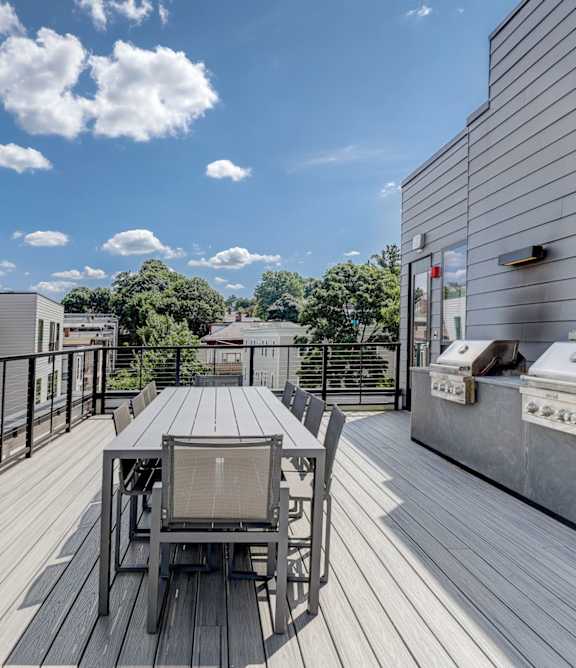 A wooden deck with a table and chairs is surrounded by buildings.