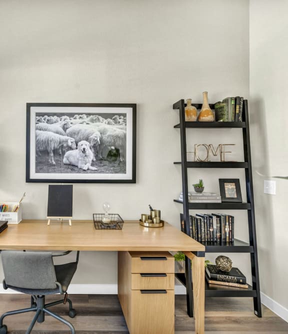 a home office with a desk and a picture of sheep on the wall