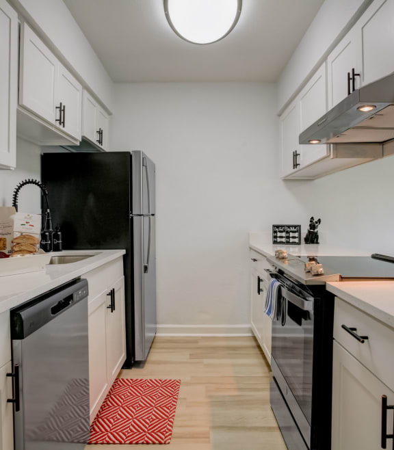 a kitchen with white cabinets and black appliances and a white counter top