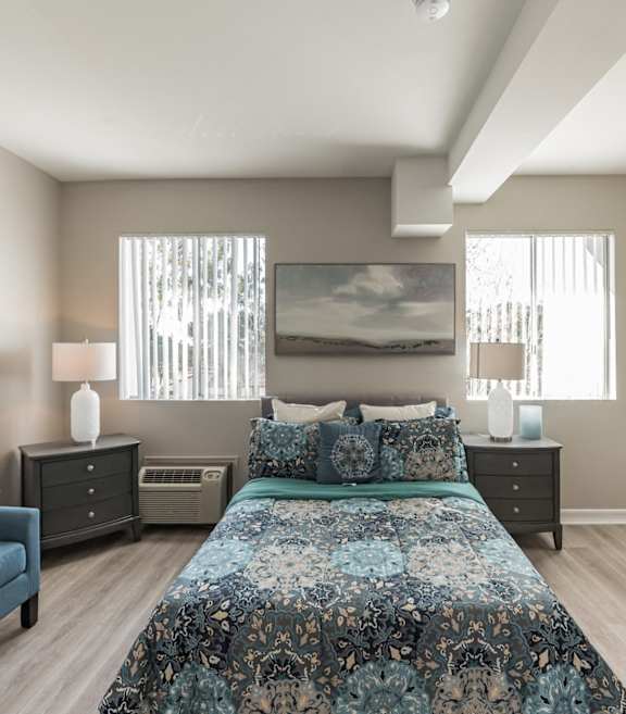 a bedroom with a bed and a desk and a chair at Legacy Hills at Poway 55+ Apartments, Poway, California