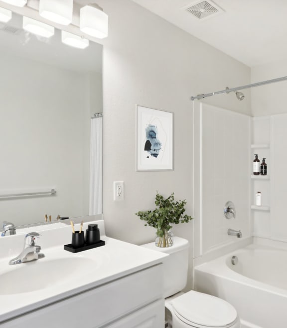 a white bathroom with a tub and a sink and a toilet