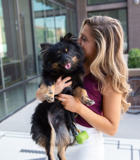 a woman is holding a small black dog