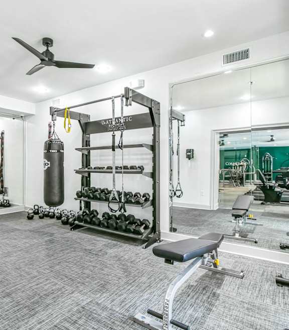 A spacious gym with a variety of equipment including a punching bag, weight racks, and a bench at The Atlantic Buckhead Apartments, Atlanta, GA, 30305