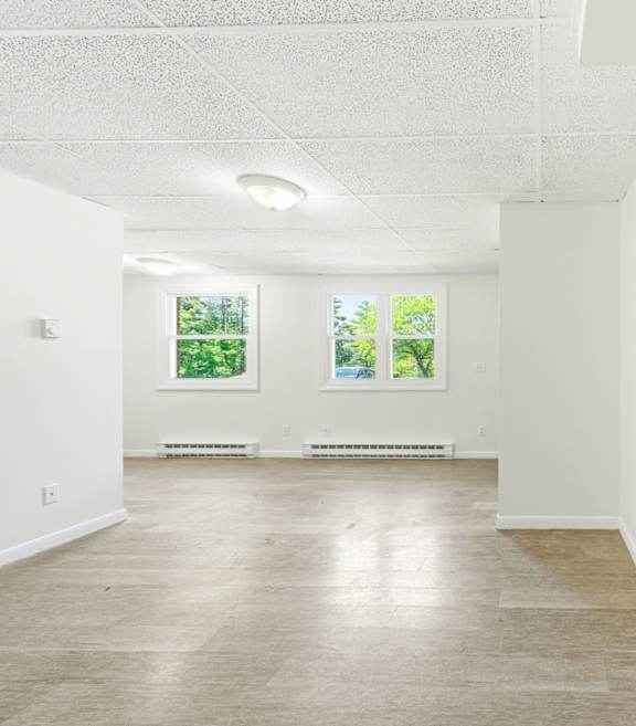 A room with a white ceiling and a window with a view of trees.