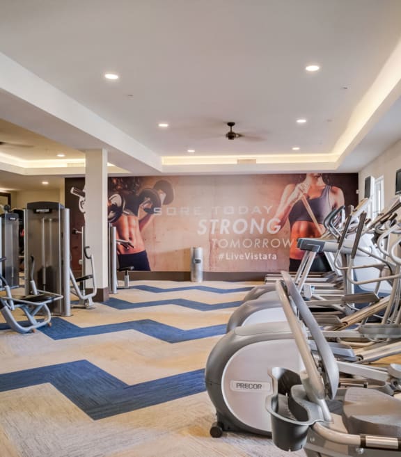 a gym with cardio equipment and weights on the floor