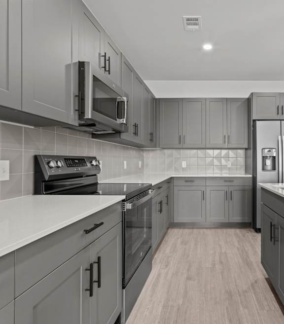 A modern kitchen with a white countertop and grey cabinets.