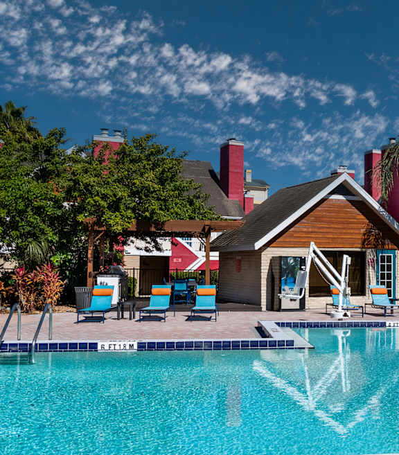 A swimming pool in front of a red and wooden building at Fusion Orlando.