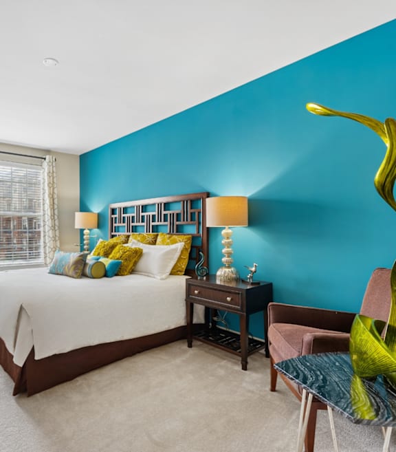 A bedroom with a bed, a chair, and a large sculpture.