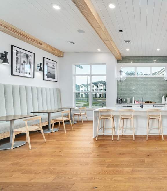 A modern kitchen with wooden floors and white bar stools.