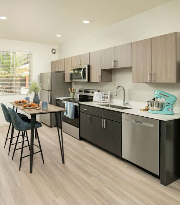 Model kitchen with stainless steel appliances and a wooden table at Cabana Southern