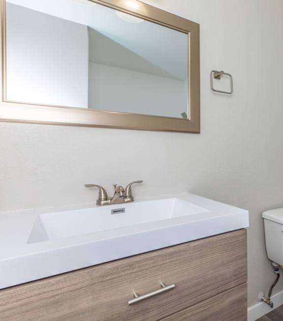 A bathroom with a toilet, sink, and mirror.