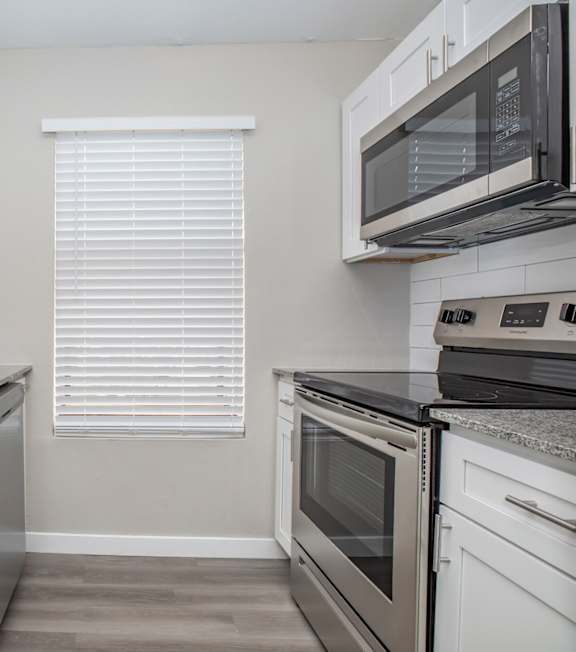 A kitchen with white cabinets and a stainless steel sink.