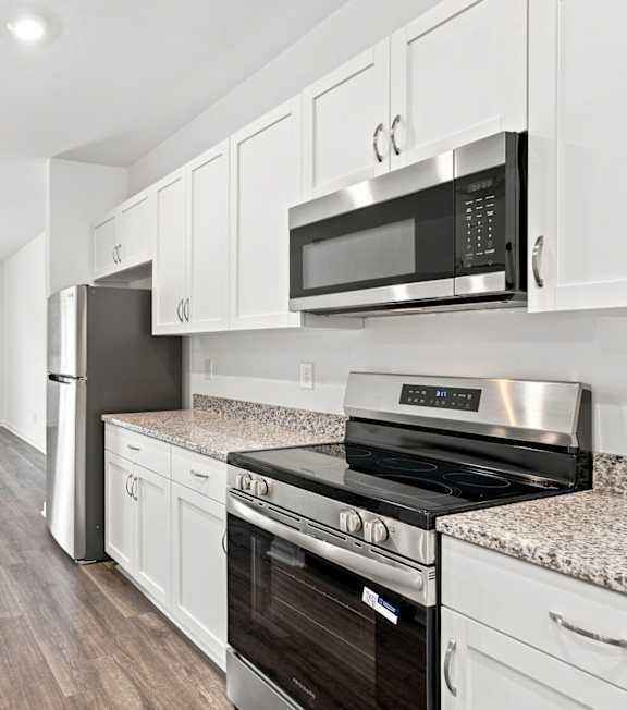 A modern kitchen with a stainless steel refrigerator, oven, and microwave.