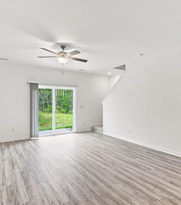 A room with a ceiling fan and sliding glass doors leading to a garden.