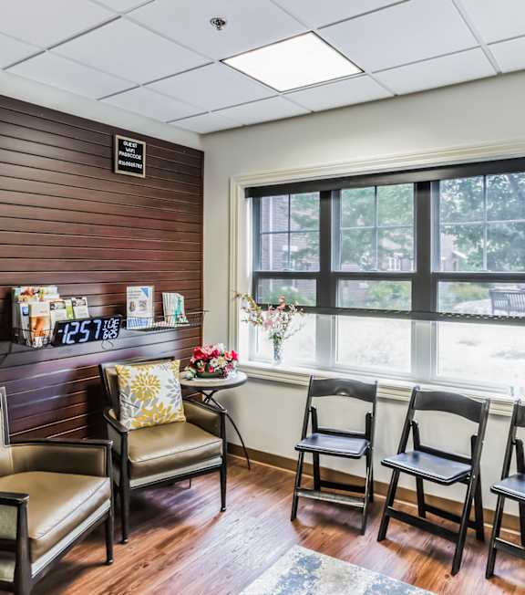 A waiting room with a bench, chairs, and a vending machine.