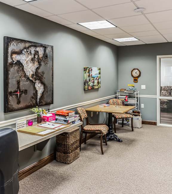 A room with a desk, chair, and a painting on the wall.