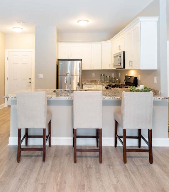 A kitchen with a center island and four chairs.
