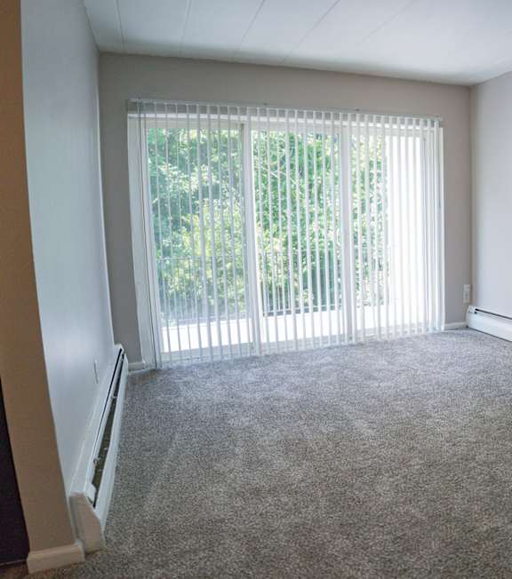 A room with a carpeted floor and a sliding glass door.
