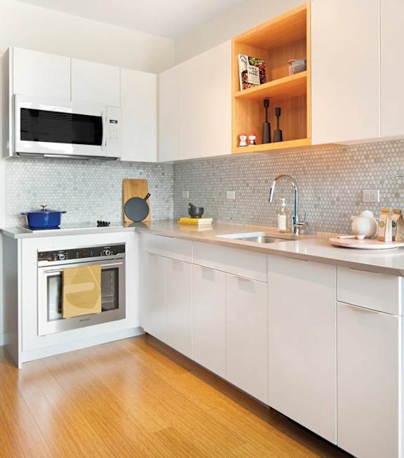 A modern kitchen with white cabinets and a wooden floor.
