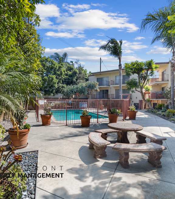 A pool with a hot tub and lounge chairs in front of a building.