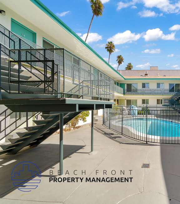 A pool with a hot tub and lounge chairs in front of a building.