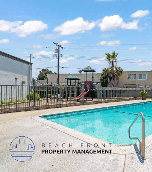 A pool with a hot tub and lounge chairs in front of a building.