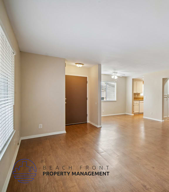 A spacious empty room with wooden floors and white walls.