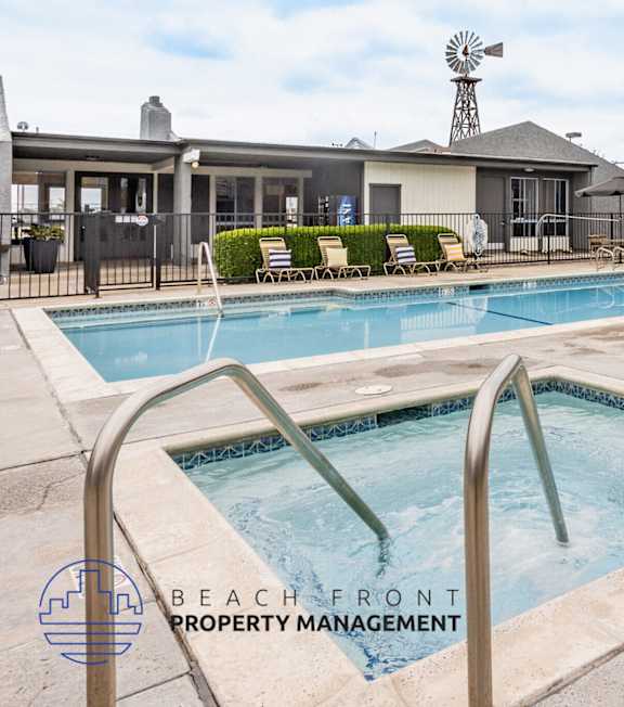 A pool with a hot tub and lounge chairs in front of a building.