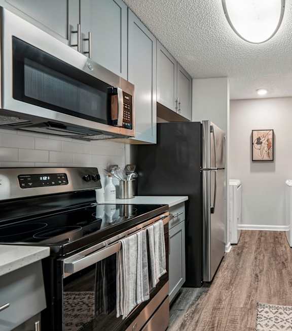 A kitchen with a refrigerator, cabinets, and a countertop.