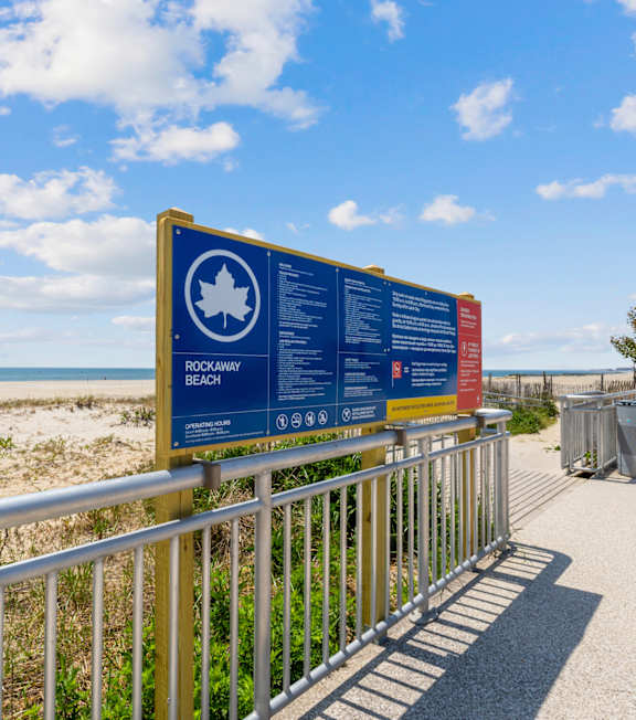 A signboard with a maple leaf on it is on a fence.