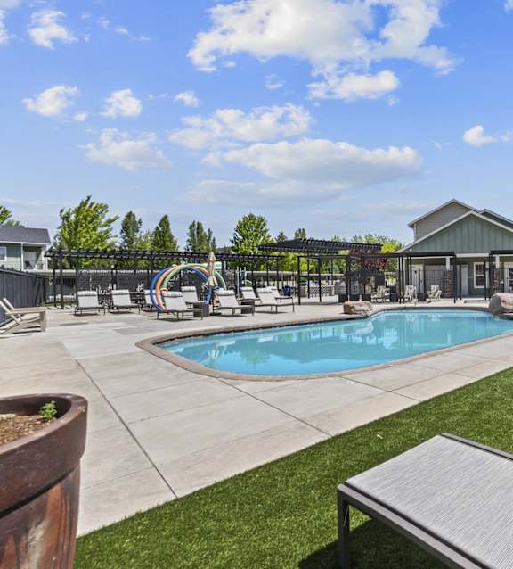 A pool area with sun loungers and a building in the background.