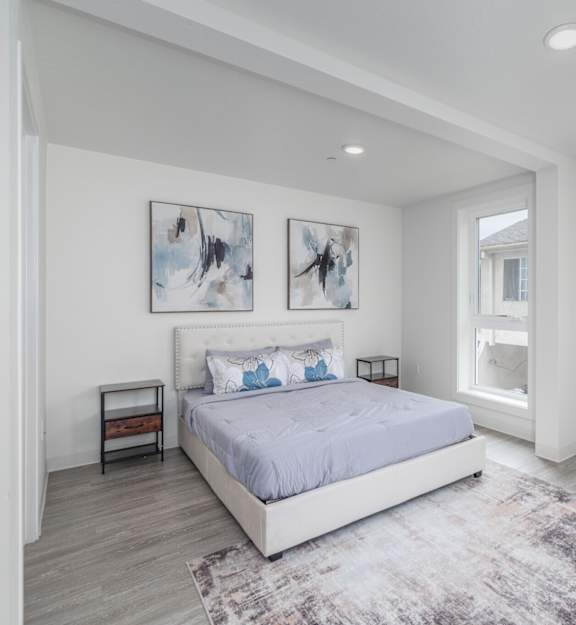 A bedroom with a large bed and two pictures on the wall.