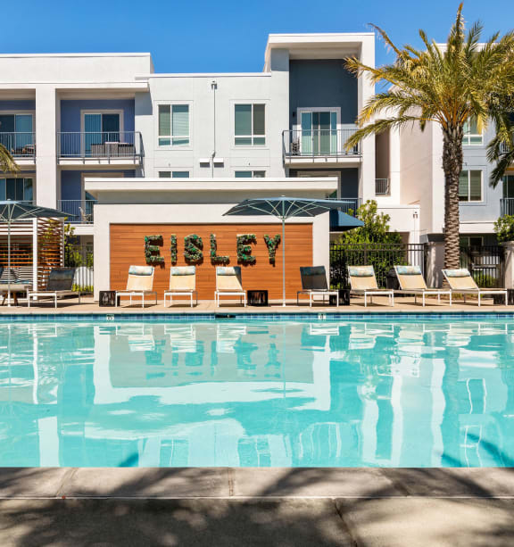 a swimming pool with a couch and tables in front of a building