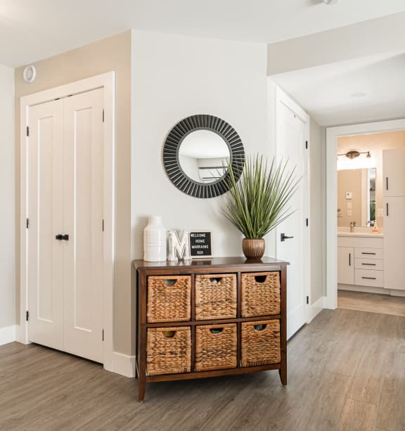 a living room with a dresser and a mirror on the wall