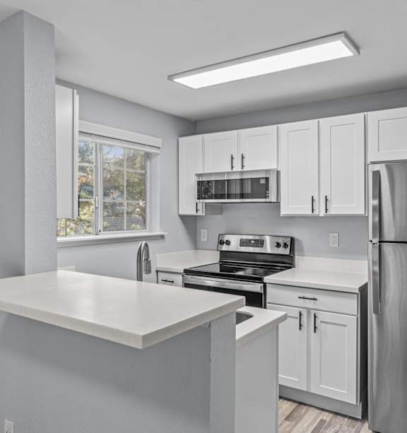 A modern kitchen with a stainless steel refrigerator and a white countertop.