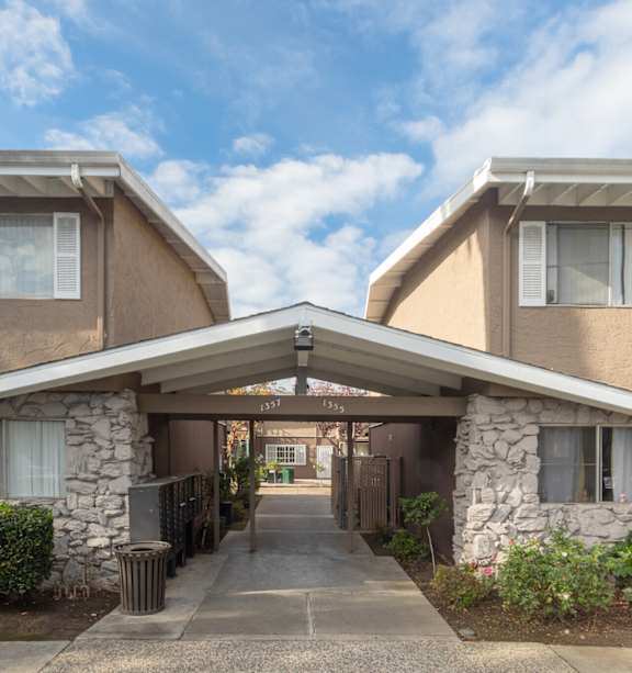 A sunny day at a residential complex with a pathway leading to a covered walkway.