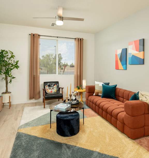 A living room with a red couch, a television, and a potted plant.
