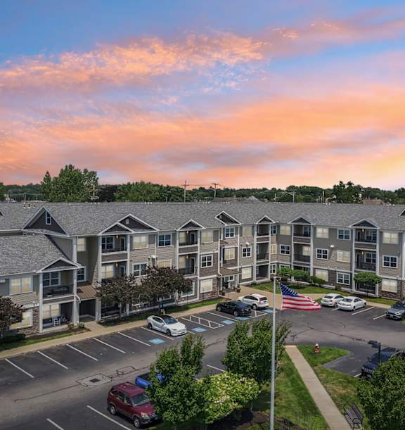 A large apartment complex with a parking lot in front.