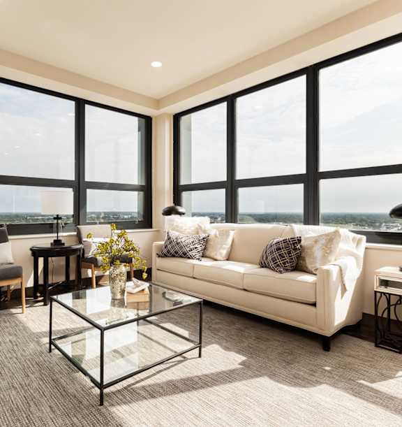 A modern living room with a glass coffee table and a large window.