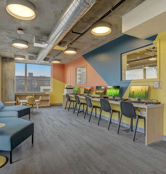 A room with a blue couch, chairs, and desks.
