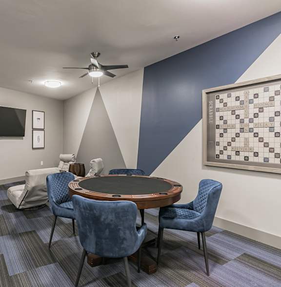 A room with a round table and chairs, a ceiling fan, and a television.