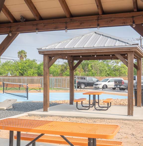 a pavilion with picnic tables at a park with a basketball court