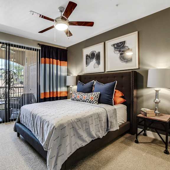 A bedroom with a queen-size bed, balcony, and nightstands at Desert Club. 
